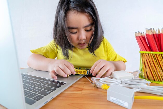 Las mujeres asiáticas están aprendiendo circuitos eléctricos simples estudiando en línea desde su computadora portátil para encontrar información sobre cómo conectar circuitos