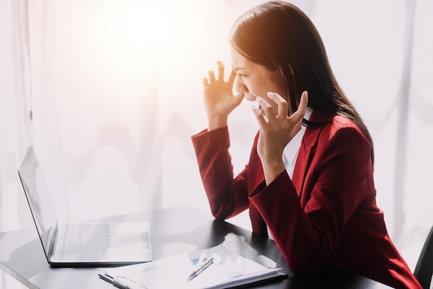 Las mujeres asiáticas están estresadas mientras trabajan en una computadora portátil Mujer de negocios asiática cansada con dolor de cabeza en la oficina sintiéndose enferma en el espacio de copia de trabajo