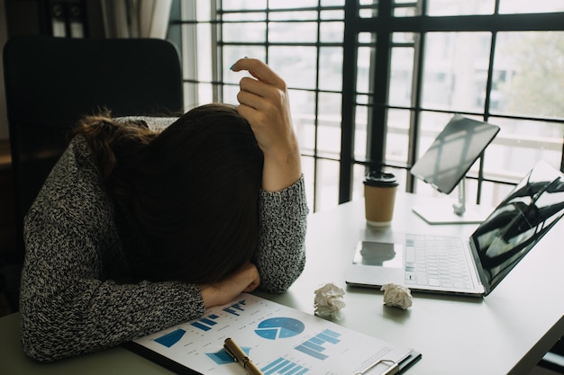 Las mujeres asiáticas están estresadas mientras trabajan en una computadora portátil Mujer de negocios asiática cansada con dolor de cabeza en la oficina sintiéndose enferma en el espacio de copia de trabajo