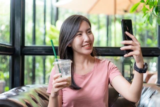 Las mujeres asiáticas están lidiando con trabajos a través de teléfonos móviles en el café.