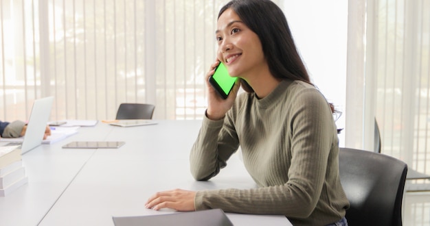 Mujeres asiáticas Estudiantes Sonreír y divertirse usando teléfonos inteligentes y tabletas