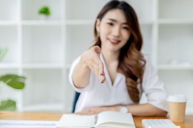 Las mujeres asiáticas extienden sus manos como si pidieran un apretón de manos, una empresaria extiende su mano hacia adelante para estrechar a un socio comercial, un apretón de manos para felicitar o presentar sus respetos después de una charla de negocios.