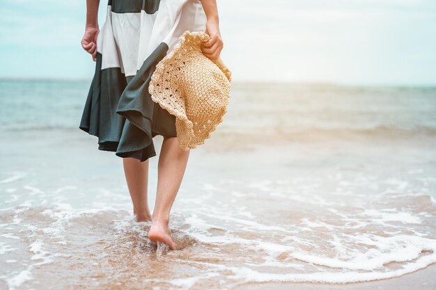 Mujeres asiáticas felices con sombrero caminando descalzo para recibir el viento y disfrutar de la vida en las vacaciones en la playa. playa, verano, liftstyle, estado de ánimo positivo, viajes, concepto de relax.