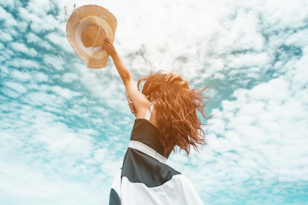 Las mujeres asiáticas felices con sombrero de sujeción se paran para recibir el viento y disfrutar de la vida en las vacaciones en la playa. playa, verano, liftstyle, estado de ánimo positivo, viajes, concepto de relax.