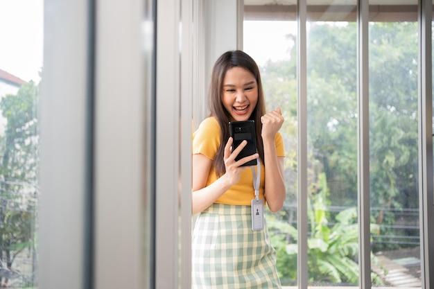 Mujeres asiáticas jóvenes felices emprendedor feliz y emocionado sonriendo después de recibir el mensaje para el éxito señal de contacto de negocios chica feliz en el lugar de trabajo aprendizaje a distancia en línea educación y trabajo