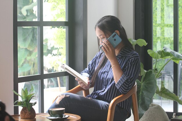 MUJERES ASIÁTICAS JÓVENES RELAJARSE LEER Y TOMAR CAFÉ EN LA CAFÉ