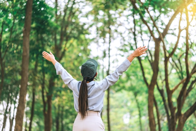 Las mujeres asiáticas levantan la mano hacia la naturaleza en el bosque, la gente se protege de la deforestación y la contaminación o el cambio climático Concepto para amar la naturaleza y la ecología del medio ambiente arbóreo y el concepto del Día de la Tierra