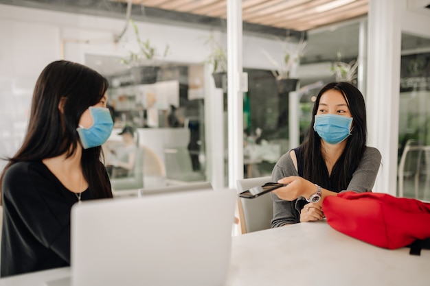 Mujeres asiáticas con mascarillas en la oficina