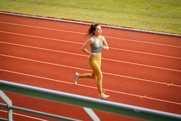 Mujeres asiáticas de mediana edad corriendo durante la mañana soleada en la pista del estadio