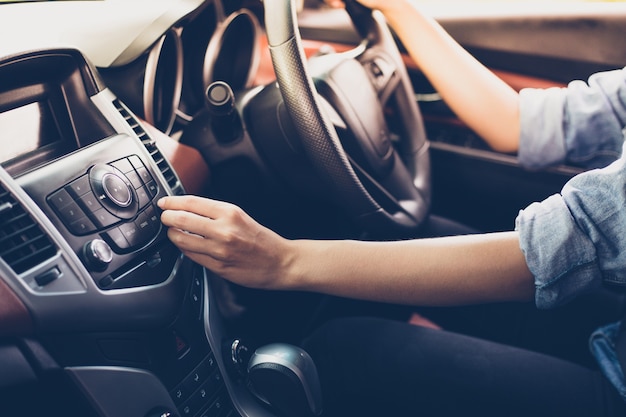 Las mujeres asiáticas presionan el botón en la radio del coche para escuchar música.