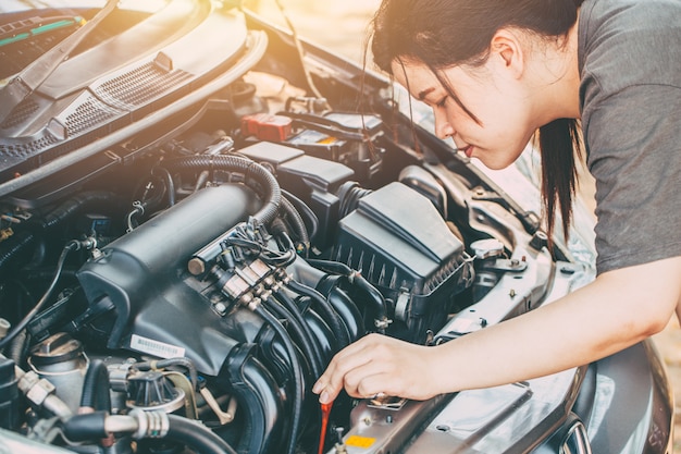 Mujeres asiáticas que controlan el motor de GLP del coche antes de ir tono de color vintage