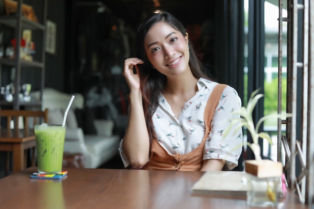 Mujeres asiáticas que sonríen y que se relajan felices con té verde en una cafetería