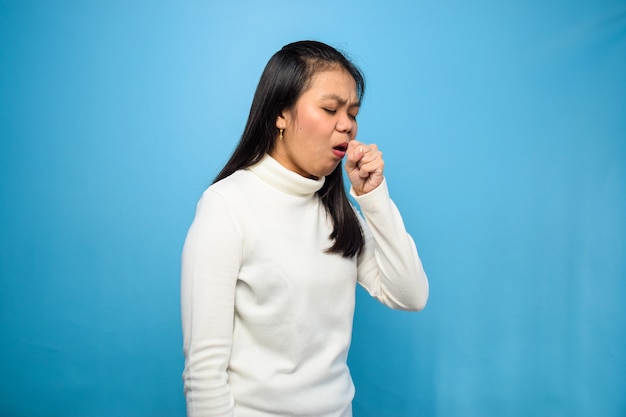 Mujeres asiáticas que usan camiseta blanca aislada en azul tosiendo debido a síntomas del virus corona