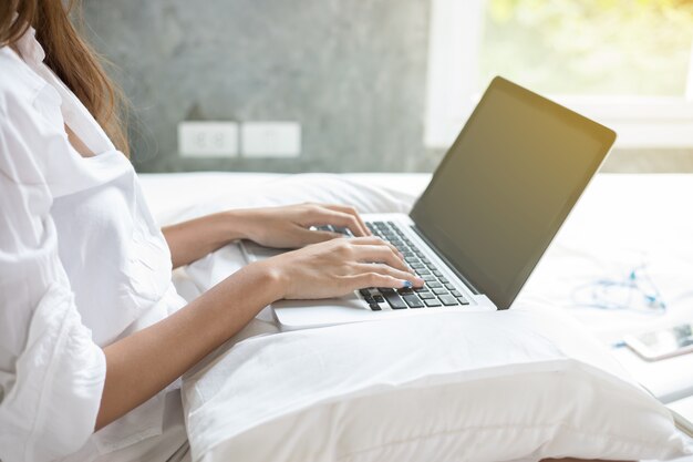 Mujeres asiáticas que usan el cuaderno y sonríen felices para trabajar en cama