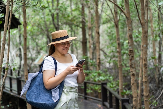 Mujeres asiáticas que viajan por el bosque natural y usan teléfonos inteligentes. Sendero para caminar en la selva tropical.