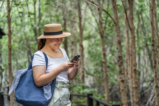 Mujeres asiáticas que viajan por el bosque natural y usan teléfonos inteligentes. Sendero para caminar en la selva tropical.