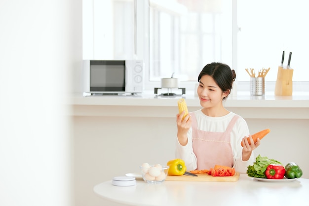 Las mujeres asiáticas se relajan en la mesa de la cocina con verduras de frutas frescas