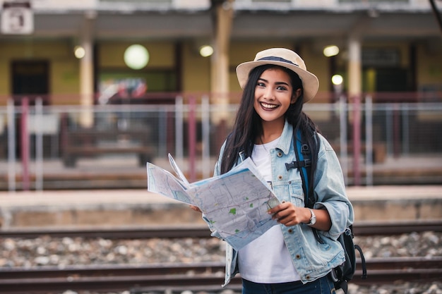 Las mujeres asiáticas sonríen con el mapa Travel Holiday en la estación de tren con un viajero Concepto de relajación