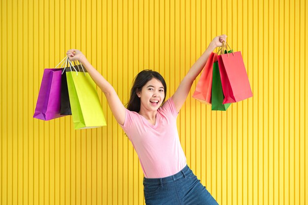 Las mujeres asiáticas sostienen una bolsa de compras en un colorido fondo amarillo, concepto de venta de verano