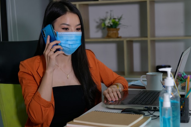 Las mujeres asiáticas trabajan en casa. Para encerrarse durante el virus corona Llevando una mascarilla y lavándote.