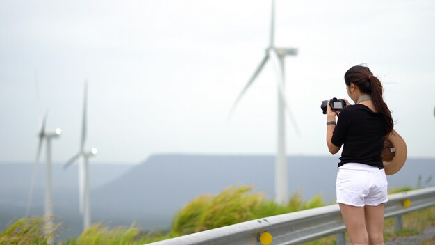 Mujeres asiáticas turistas están tomando una foto de un aerogenerador en un lugar pintoresco.