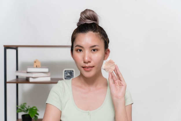 Las mujeres asiáticas usan almohadillas de algodón humedecidas con toallitas limpiadoras para quitarse el maquillaje de la cara