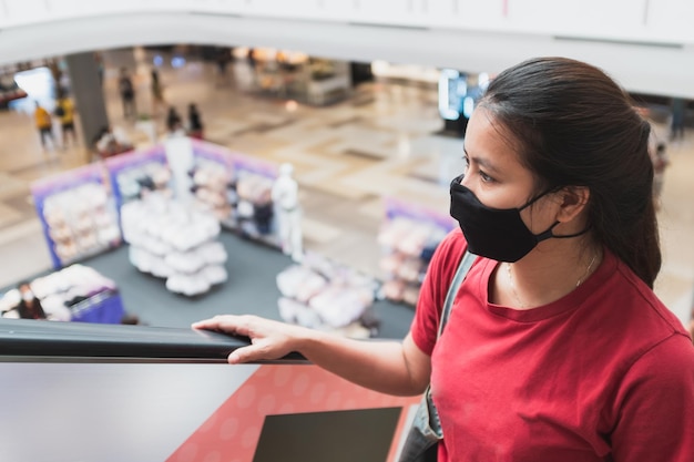 Foto mujeres asiáticas usan máscaras médicas y usan escaleras mecánicas en centros comerciales