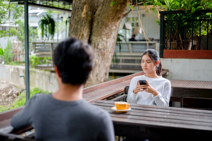 Mujeres asiáticas usando mensajes de escritura en un teléfono móvil en la cafetería