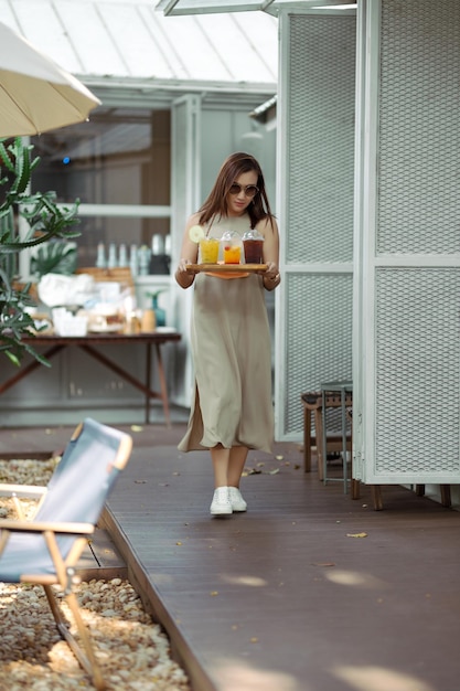 Mujeres asiáticas con vestidos largos sirven café y jugo de frutas en la cafetería Mujer caminando y sosteniendo una bandeja de café Autoservicio en una cafetería