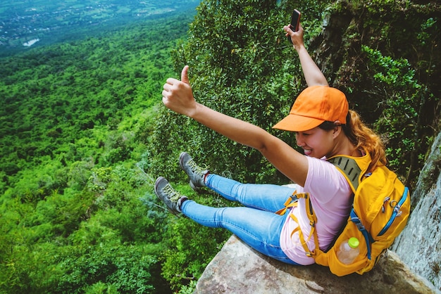 Las mujeres asiáticas viajan a relajarse en las vacaciones. Siéntate en el acantilado. en la montaña