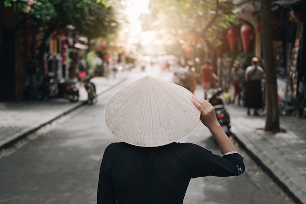 Las mujeres asiáticas viajan a relajarse en las vacaciones. su mano tocó el sombrero y miró la vista del casco antiguo de da nang.