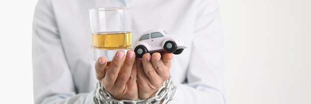 Las mujeres atadas con cadena sostienen el vidrio con alcohol y adicción al alcohol de coches de juguete y borracho