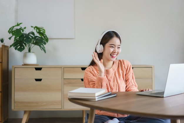 Mujeres con auriculares y saludando a sus amigos en videoconferencia en la computadora portátil en el estilo de vida en casa