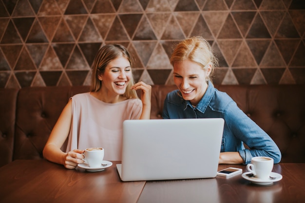 Mujeres bastante jovenes con la computadora portátil por la tabla