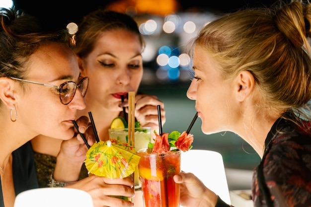 Mujeres bebiendo cócteles juntas en una terraza por la noche