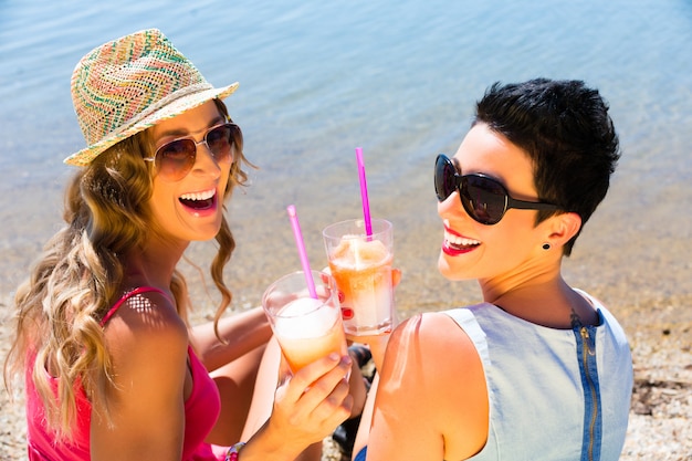 Mujeres bebiendo cócteles en la playa