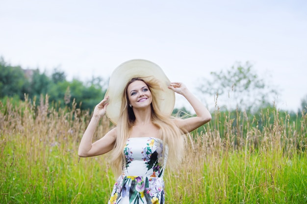 Mujeres de belleza en un sombrero de paja solo con la naturaleza