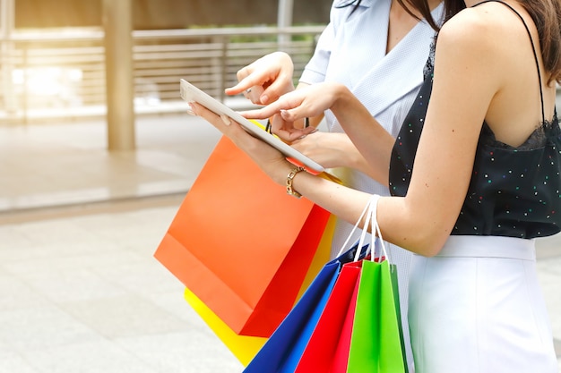 Mujeres con bolsas de compra y tableta.