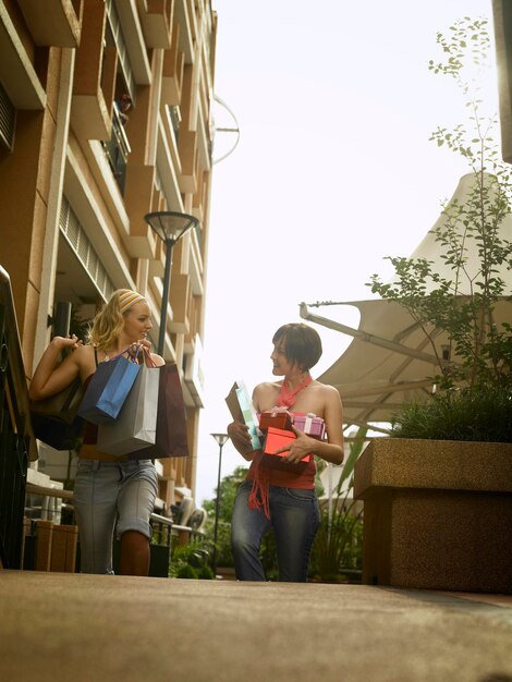 Foto mujeres con bolsas de compras y cajas de regalos en la acera