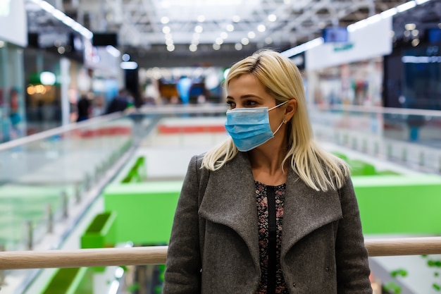 Mujeres bonitas con polvo de protección de máscara en el centro comercial, enfoque selectivo.