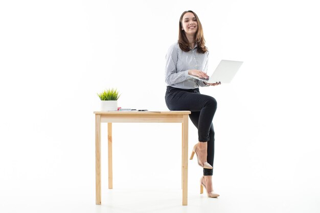 Foto las mujeres de buen humor están sentadas en una mesa y escribiendo en una computadora con un fondo blanco