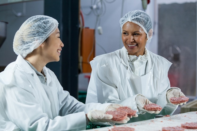 Mujeres carniceros procesando hamburguesa