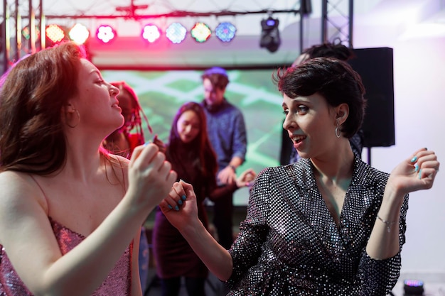 Mujeres caucásicas jóvenes bailando en un espectáculo de música en vivo en un club nocturno. Dos amigas de fiesta y de club en la pista de baile juntas, disfrutando de la actividad de entretenimiento de la vida nocturna