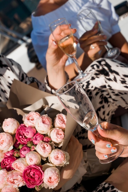 Las mujeres celebran. La muchacha sostiene un ramo de rosas y copas con champán. De cerca