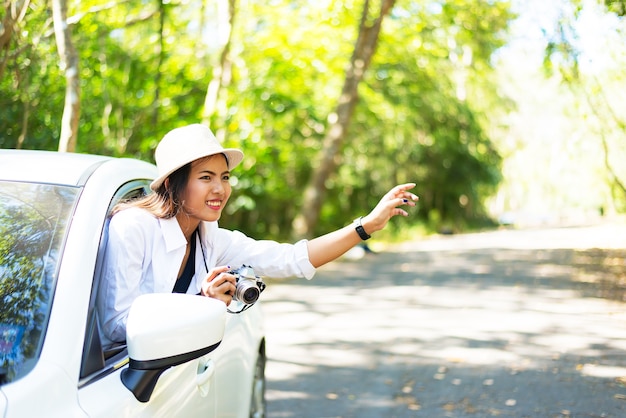 mujeres con el coche en el camino de otoño mirando en el mapa de viaje