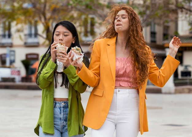 Mujeres comiendo comida callejera al aire libre