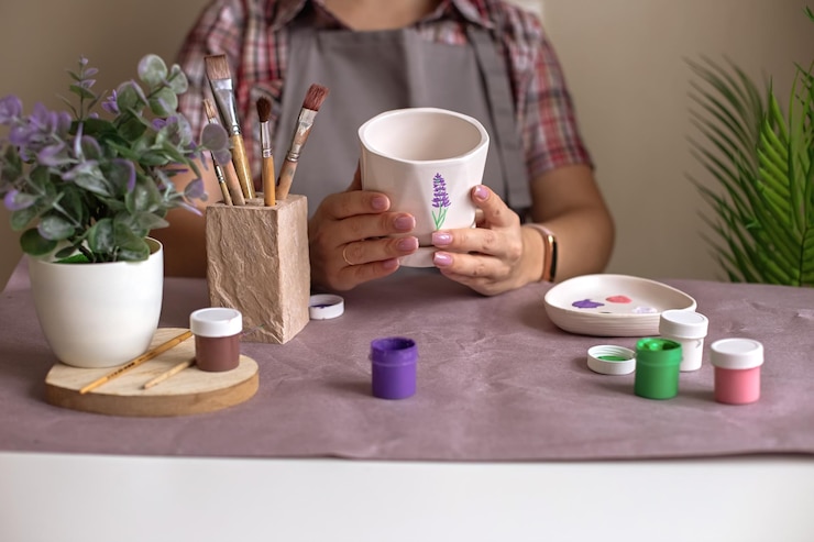 Foto las mujeres con delantal gris sostienen una maceta de cerámica con flores blancas.