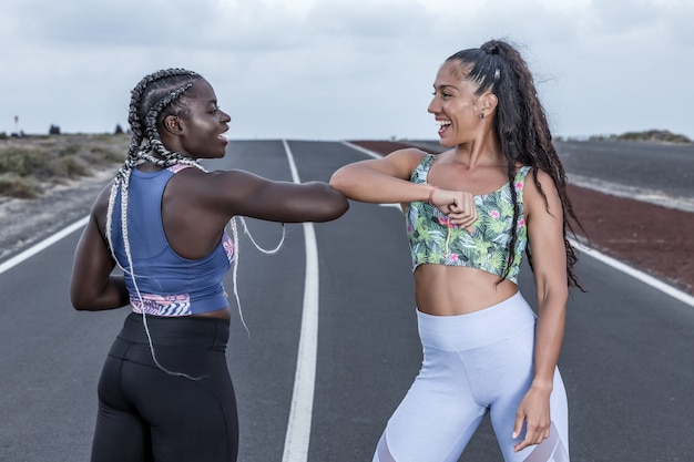 Mujeres deportistas felices saludándose con el codo