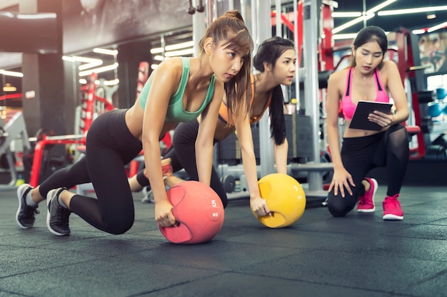 Las mujeres deportivas hacen ejercicio juntos en el gimnasio con entrenador