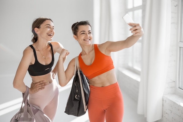 Mujeres deportivas haciendo selfie en el gimnasio